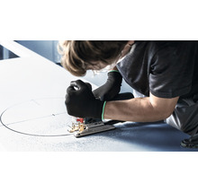 Eine Person sägt mit einer Stichsäge einen Kreis in eine Platte.