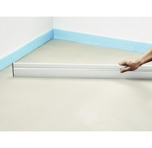 Person nivelliert Estrich mit Richtscheit und Dämmstreifen an der Wand