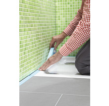 Handwerker dichtet Duschwanne mit Dichtband im Badezimmer ab.