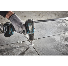 Bediener befestigt Terrassenplatten mit einer Bohrmaschine und Nivelliertellern