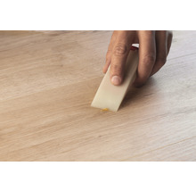 Person repariert Holzboden mit Reparaturwachs