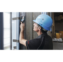 Ein Bauarbeiter verwendet einen Detektor zur Wandprüfung auf einer Baustelle.