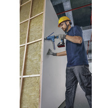 Ein Handwerker befestigt eine Gipskartonplatte mit einem Magazinschrauber an einer Wand.