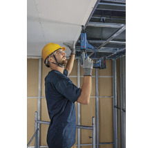 Ein Mann befestigt mit einem Trockenbauschrauber eine Gipskartonplatte an einer Decke.