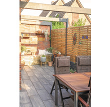 Terrasse mit Sitzbereich, Holzzaun und Pflastersteinen