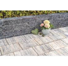 Gestapelte Mauersteine bilden eine kleine Mauer, ergänzt durch Gehwegplatten und dekorative Elemente