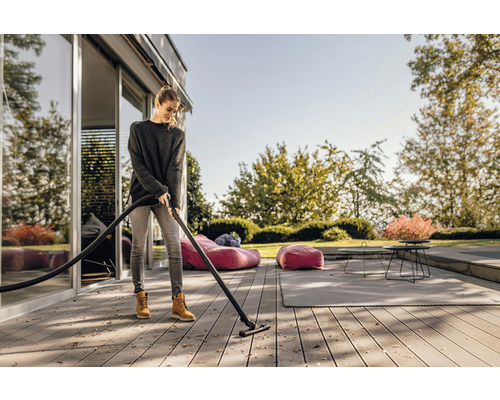 Frau reinigt Terrasse mit einem Nass-Trockensauger.