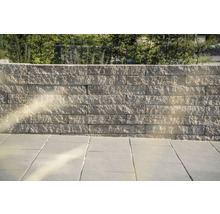 Eine Mauer aus Steinblöcken und ein Boden aus Steinplatten im Außenbereich.