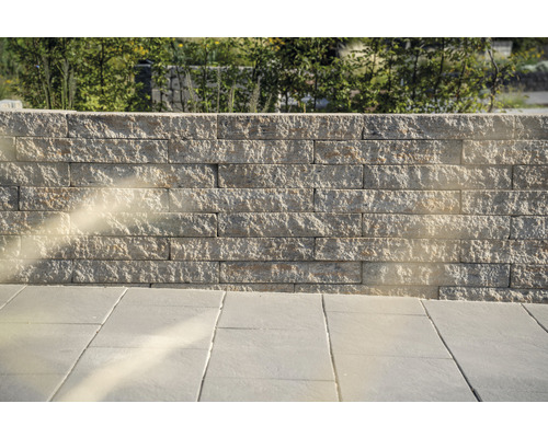 Eine Mauer aus Steinblöcken und ein Boden aus Steinplatten im Außenbereich.