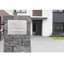Briefkastenanlage aus Edelstahl an einer Steinmauer vor einem Wohnhaus