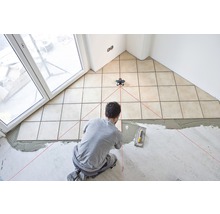 Fliesenleger verlegt Fliesen mit Hilfe eines Laser-Nivelliergeräts