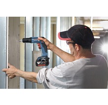 Handwerker schraubt Gipskartonplatte mit einem Akku-Trockenbauschrauber an eine Metallkonstruktion