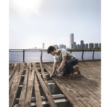 Handwerker verlegt mit einer Stichsäge Holzdielen auf einer Terrasse