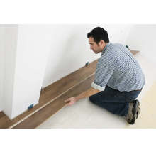 Mann verlegt Laminatboden im Innenraum