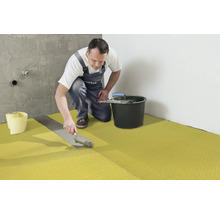 Handwerker verlegt Entkopplungsmatte im Badezimmer.