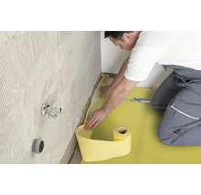 Handwerker verlegt Dichtband in einem Badezimmer.