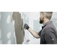 Mann spachtelt Wand mit Spachtelmasse
