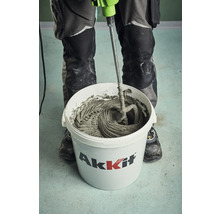 Ein Handwerker mischt Fliesenkleber in einem Eimer der Marke Akkit mit einem elektrischen Rührgerät.