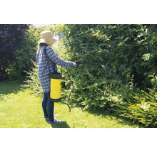 Frau verwendet eine Gartenspritze im Garten zur Schädlingsbekämpfung an Pflanzen.