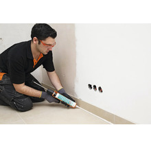 Handwerker verwendet Dichtstoffpistole zum Abdichten einer Sockelleiste