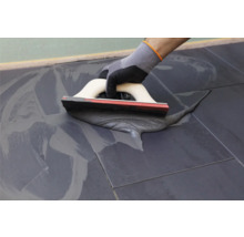 Handwerker verwendet eine Spachtel zum Verfugen von Fliesen.