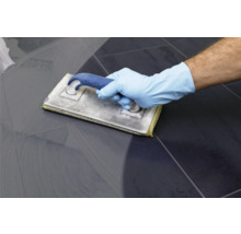 Fliesenleger mit Fugbrett beim Verfugen von Fliesen