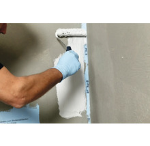 Anstreichen einer Wand mit einer Farbwalze neben einem Abdichtband