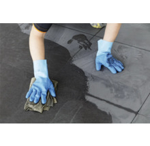 Eine Person wischt mit einem Tuch und Handschuhen Fliesen.