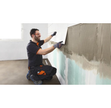 Fliesenleger bei der Wandverfliesung im Innenbereich.