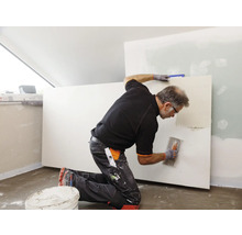 Handwerker spachtelt eine Trockenbauwand mit einer Glättkelle