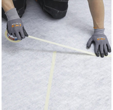 Handwerker verklebt Abdeckvlies mit Klebeband auf dem Boden