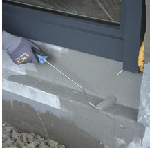 Auftragen einer Abdichtung mit einer Walze an einer Hauswand.