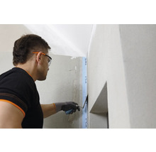 Eine Person glättet Putz an einer Wand mit einer Spachtel.