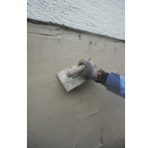 Auftragen von Putz auf eine Wand mit einer Glättkelle