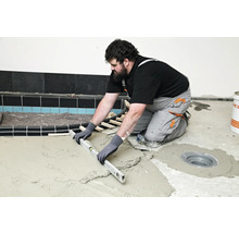 Handwerker nivelliert Estrich mit einer Wasserwaage im Badezimmer.