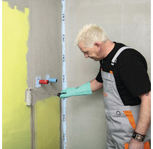 Handwerker trägt Dichtschlämme mit einer Farbwalze auf die Wand im Badezimmer auf.