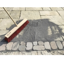 Besen zum Einkehren von Pflastersand auf einer gepflasterten Fläche