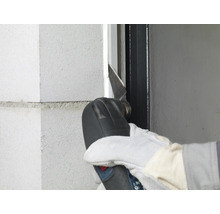 Person verwendet ein Multifunktionswerkzeug zum Schneiden an einer Wand