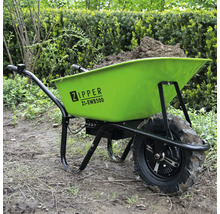 Grüne Schubkarre mit Erdfüllung im Garten