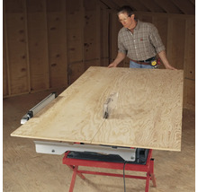 Mann schneidet Holzplatte mit einer Tischkreissäge.