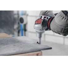 Handwerker bearbeitet Steinplatte mit einem Bohrgerät