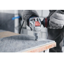 Ein Bediener bohrt mit einer Fliesenbohrmaschine ein Loch in eine Fliese.