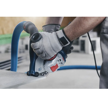 Mann benutzt Mauernutfräse mit Staubabsaugung zum Schneiden von Stein