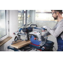 Gehrungssäge beim Schneiden eines Holzstücks, bedient von einem Handwerker