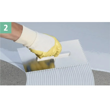 Eine Person, die mit einer Zahnspachtel Klebstoff aufträgt.