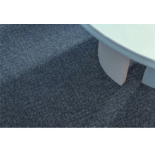 Detailansicht eines blauen Teppichs neben einem weißen Tisch.