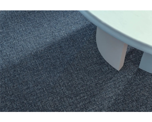 Detailansicht eines blauen Teppichs neben einem weißen Tisch.