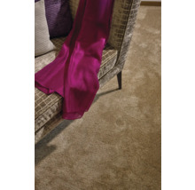 Detailansicht eines Wohnzimmers mit einem Teppich, einem Sessel und dekorativen Kissen.