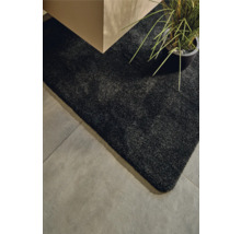 Detailansicht eines schwarzen Teppichs neben einem Tisch und einer Zimmerpflanze