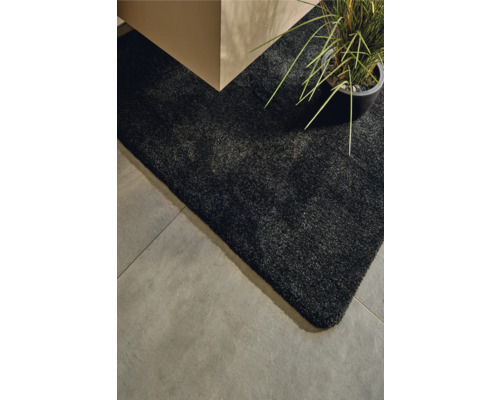 Detailansicht eines schwarzen Teppichs neben einem Tisch und einer Zimmerpflanze